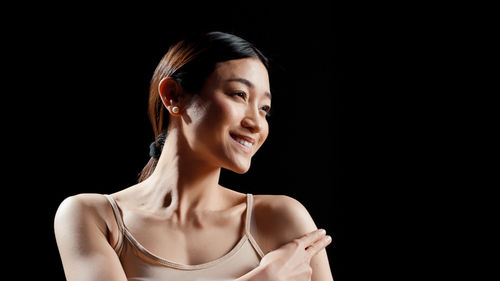 Young woman looking away against black background