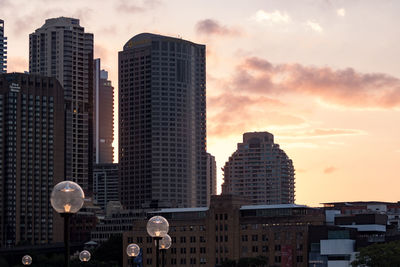 Modern buildings in city against sky during sunset