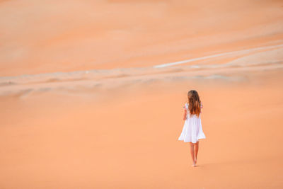 Full length of woman standing against orange sky