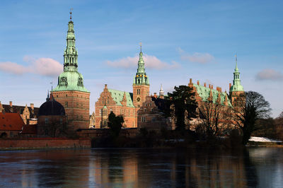 Buildings by river against sky in city