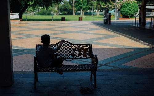Rear view of boy sitting on park bench