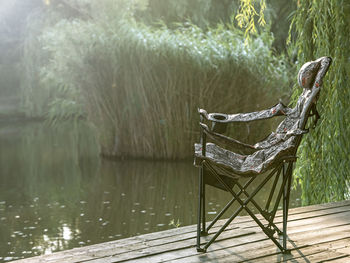 Empty camping chair on the pier near the river, summer sunny day, selective focus