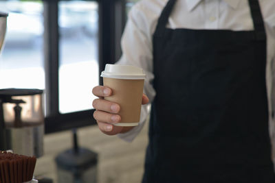 Midsection of man holding coffee cup