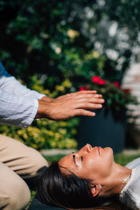 Woman in reiki spiritual healing session. reiki therapist holding hands above heart chakra 