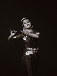 Portrait of woman standing against black background