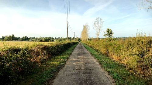 Road amidst field against sky