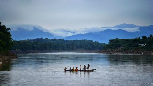 People in boat on lake against sky
