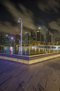 Illuminated city by buildings against sky at night