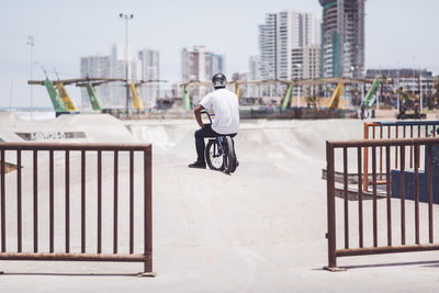 Rear view of man riding bicycle in city