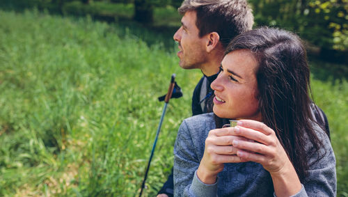 Young woman looking away while sitting on grass