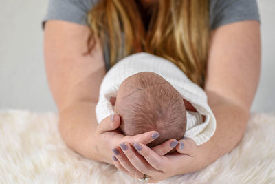 Midsection of mother holding baby boy on bed