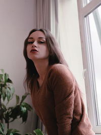 Young woman looking away while standing at home and look at the camera