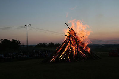 Bonfire on field against sky at sunset