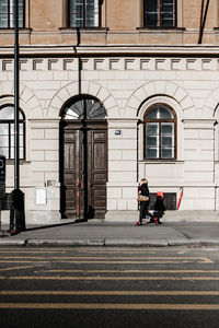 Man walking on footpath against building