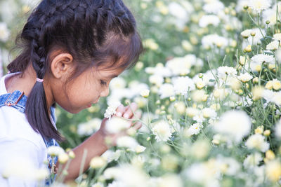 Side view of girl smelling flower at park