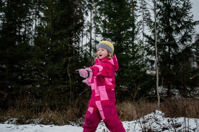 Girl playing in the snow laughing throwing a snowball