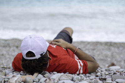 Rear view of man sitting on rock at beach