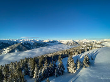 Scenic view of snow covered mountains against clear blue sky