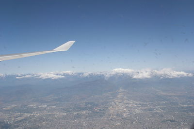 Aerial view of aircraft wing over landscape against clear sky