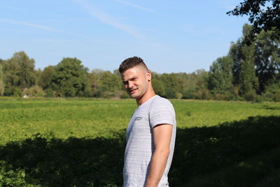 Portrait of young man standing against trees