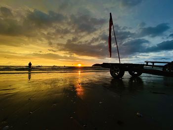 Silhouette people on beach against sky during sunset