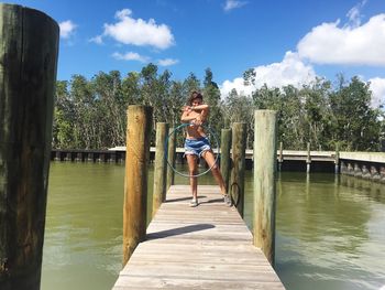 Woman on pier by lake against sky