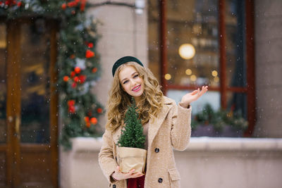 A young beautiful girl in a beige coat and a burgundy skirt is walking through a snowy city