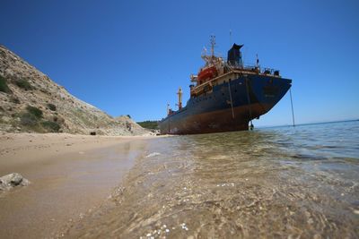 Abandoned boat on beach against clear sky