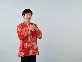 Portrait of boy standing against red background