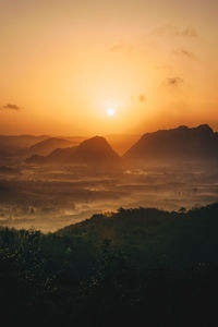 Scenic view of dramatic sky over silhouette landscape during sunset