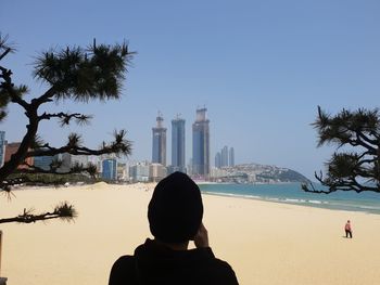 Rear view of people on beach against clear sky