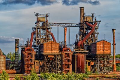 Cranes in abandoned factory against sky