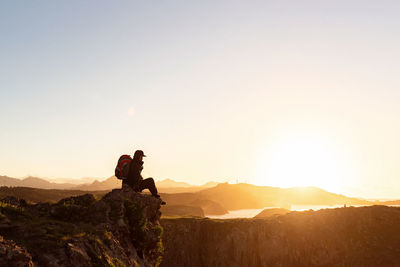 People standing on mountain against sky during sunset