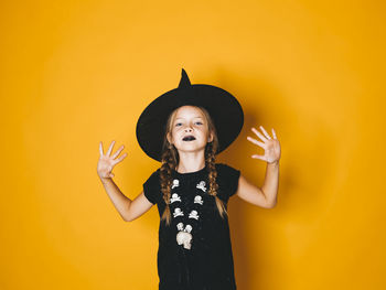 Full length of a girl standing against yellow background