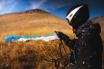 Paraglider lands or rises on the yellow grass on a sunny day. a man after or before a paragliding