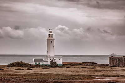 Lighthouse by sea against sky