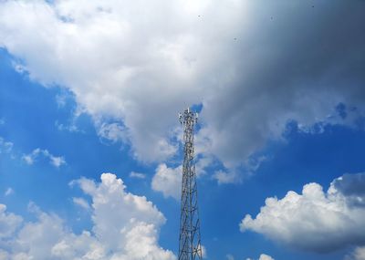 Low angle view of communications tower against cloudy sky