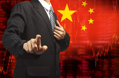 Digital composite image of businessman gesturing while standing against chinese flag