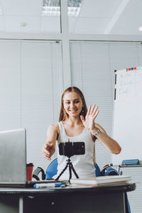 Young woman blogging over smart phone at home