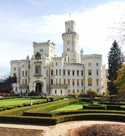 Garden by historical building against sky