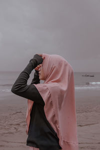 Midsection of woman standing on beach against sky