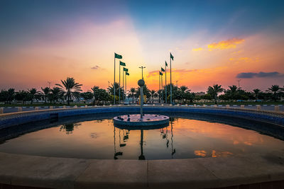 Scenic view of swimming pool by lake against sky during sunset