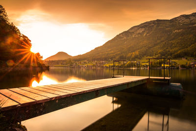 Scenic view of lake by mountains against sky during sunset