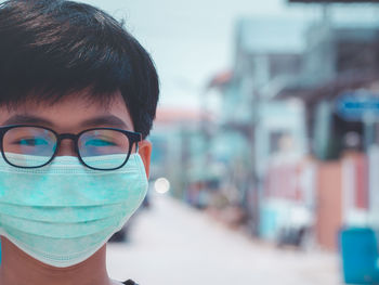 Close-up portrait of boy wearing pollution mask in city