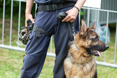 Midsection of security guard with german shepherd dog