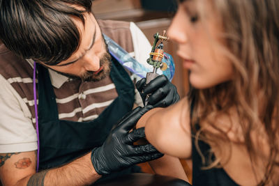 Close-up of mam making tattoo on woman hand