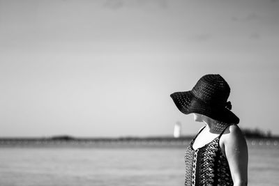 Side view of woman standing by sea against sky