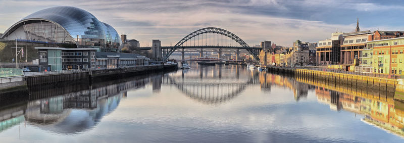 Arch bridge over river against buildings in city