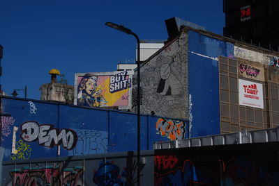 Low angle view of graffiti on building against blue sky