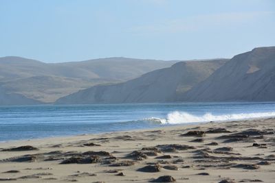 Scenic view of sea and mountains against clear sky